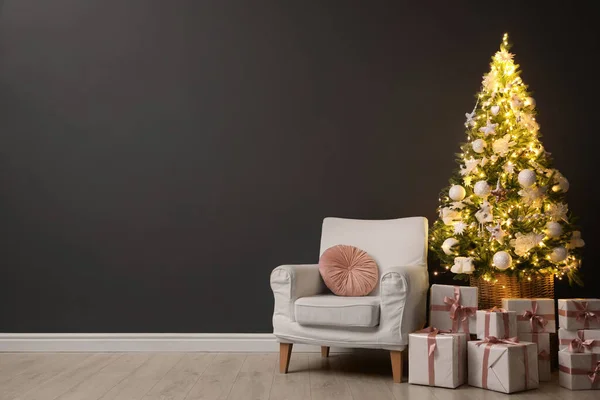 Gyönyörűen Díszített Karácsonyfa Ajándékdobozok Fotel Közelében Fekete Fal Beltérben Hely — Stock Fotó