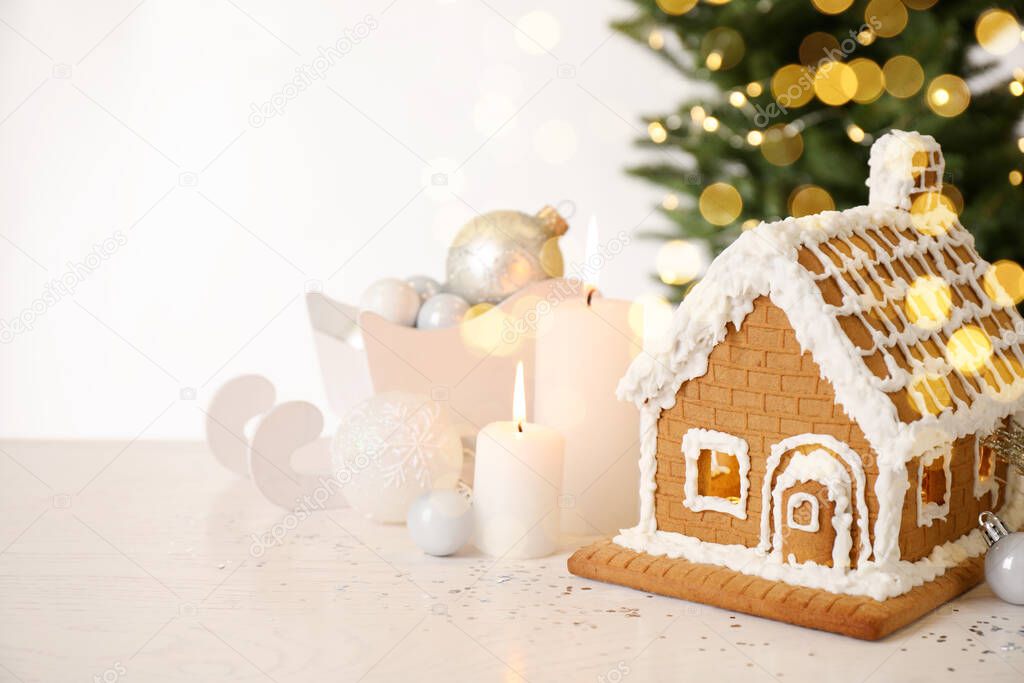Beautiful gingerbread house decorated with icing and candles on white table