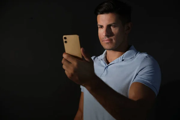 Man unlocking smartphone with facial scanner on black background. Biometric verification