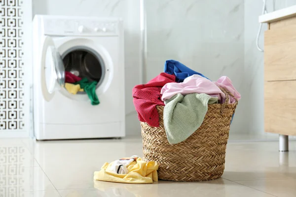 バスルームの洗濯機の近くの床に異なる服を持つウィッカー洗濯バスケット テキストのスペース — ストック写真