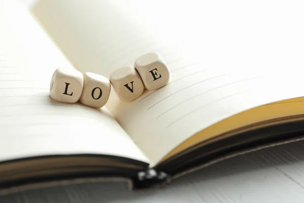 Word Miłość Wykonana Drewnianych Kostek Otwartym Notatniku Zbliżenie — Zdjęcie stockowe