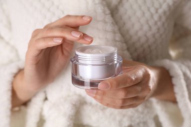 Elinde bir kavanoz nemlendirici krem olan kadın, yakın plan.