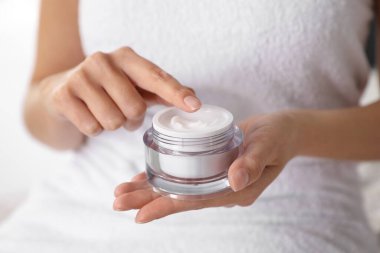 Elinde bir kavanoz nemlendirici krem olan kadın, yakın plan.