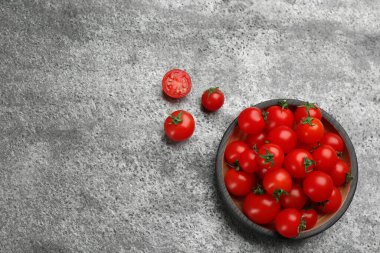 Taze vişneli domates ve tahta kase gri masada, düz yerde. Metin için boşluk