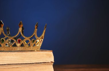 Koyu mavi arka plana karşı eski kitaplardaki güzel altın taç, yazı için yer. Fantezi ögesi