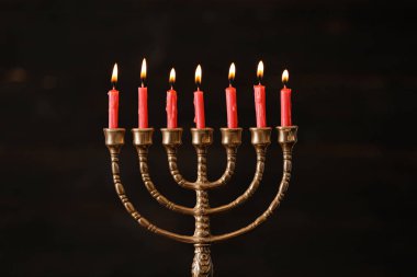 Bulanık arkaplanda yanan mumlarla altın menorah.