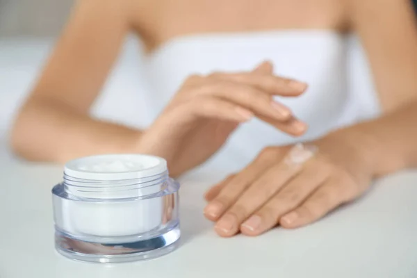 Mujer Aplicando Crema Hidratante Mesa Blanca Primer Plano —  Fotos de Stock