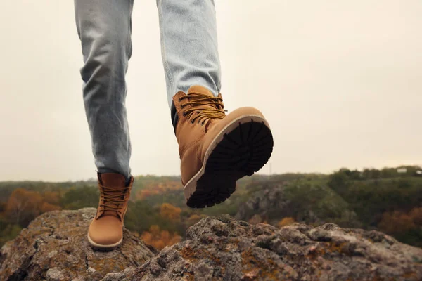 Man wearing stylish hiking boots on steep cliff, closeup