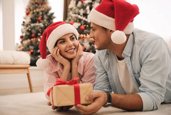 ハッピーカップルでサンタ帽子クリスマスギフトとともに自宅 — ストック写真