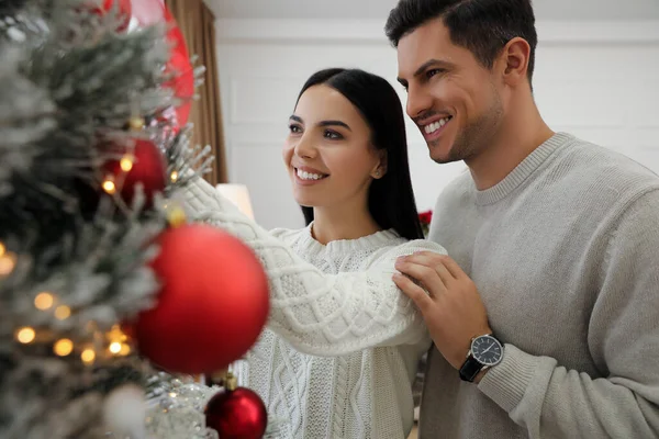 幸せなカップル飾るクリスマスツリー自宅で — ストック写真