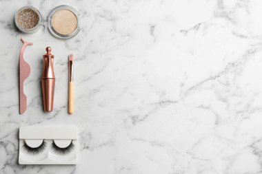 Flat lay composition with magnetic eyelashes and accessories on white marble table. Space for text