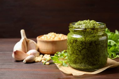 Lezzetli roka pesto kavanozu ve ahşap masada malzemeler. Metin için boşluk