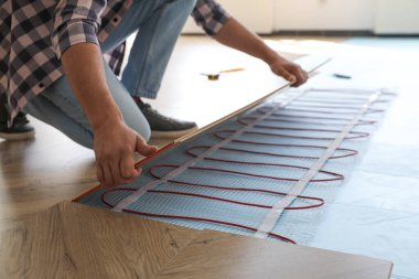 Profesyonel müteahhit zemin altı ısıtma sistemini içeri yerleştiriyor, yakın plan.