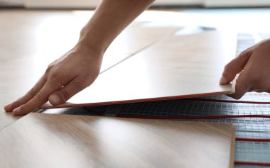 Profesyonel müteahhit zemin altı ısıtma sistemini içeri yerleştiriyor, yakın plan.