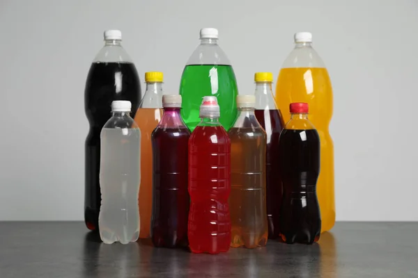 Flaschen Softdrinks Auf Dem Tisch Vor Grauem Hintergrund — Stockfoto