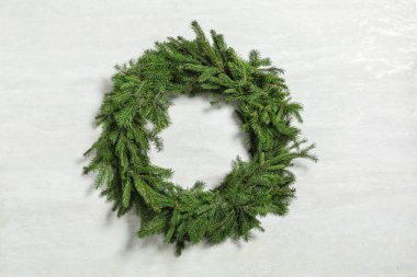 Beyaz arkaplanda köknar dallarından yapılmış Noel çelengi