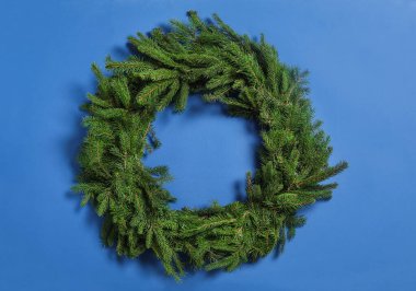 Christmas wreath made of fir branches on blue background