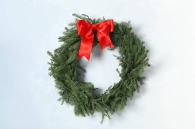 Christmas wreath made of fir branches with red bow on light wall