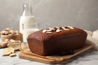 Delicious gingerbread cake with almond petals on white marble table, space for text