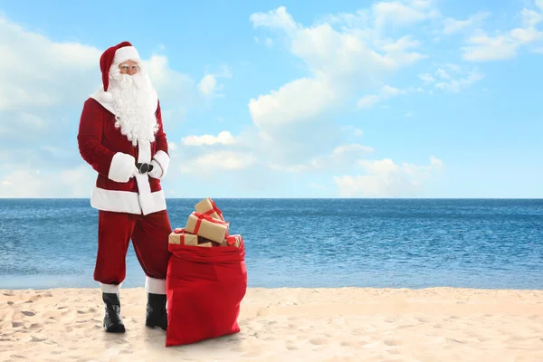 Święty Mikołaj Pobliżu Worka Prezentów Piaszczystej Plaży Miejsce Tekst — Zdjęcie stockowe