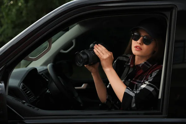 Private detective with camera spying from car