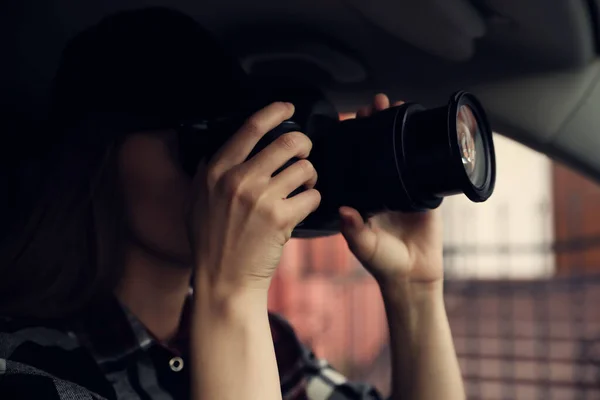 Private detective with camera spying from car, focus on lens