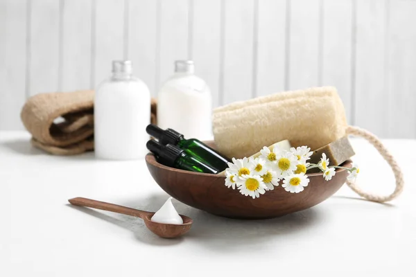Composition with chamomile flowers and cosmetic products on white table