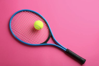Tenis raketi ve top pembe arka planda, üst manzara. Spor malzemeleri.