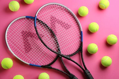 Tenis raketleri ve pembe arka planda toplar, düz yatış. Spor malzemeleri.