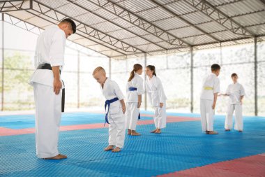 Kimono 'da çocuklar ve koç açık havada karate antrenmanından önce eğilip ritüel yapıyorlar.