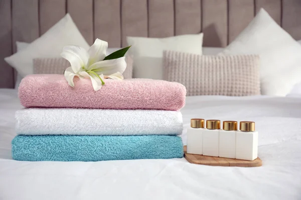 Stapel Sauberer Handtücher Blumen Und Shampooflaschen Auf Dem Bett — Stockfoto