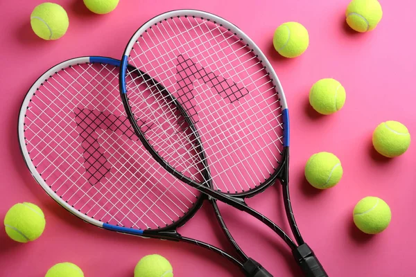 Tenis raketleri ve pembe arka planda toplar, düz yatış. Spor malzemeleri.