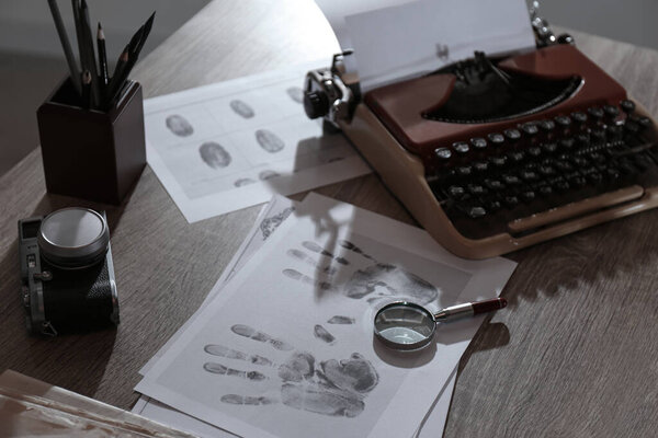 Typewriter, fingerprints and papers on desk in office. Detective's workplace