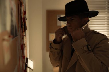 Dedektif ofisindeki kanıt panosuna bakıyor.