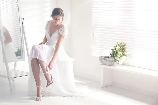 Молодая Невеста Красивом Свадебном Платье Надевает Обувь Возле Зеркала Помещении — стоковое фото