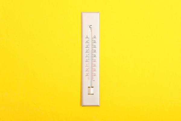 挂在亮黄色墙壁上的温度计 — 图库照片