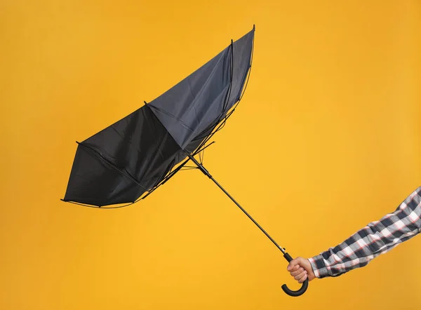 男子手持雨伞 在黄色的背景上被大风夹住 特写镜头 — 图库照片