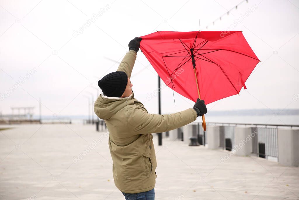 Man with red umbrella caught in gust of wind outdoors