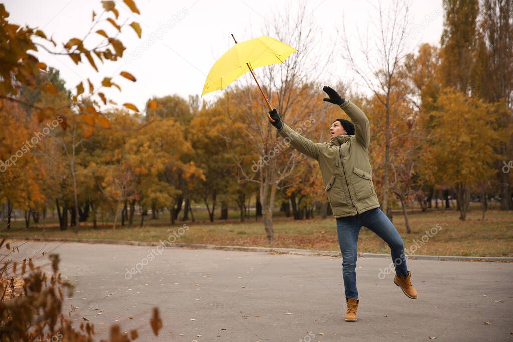 Man with yellow umbrella caught in gust of wind outdoors