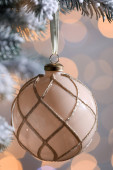 Vánoční stromeček zdobený vánoční koulí proti rozmazaným světlům, detailní záběr