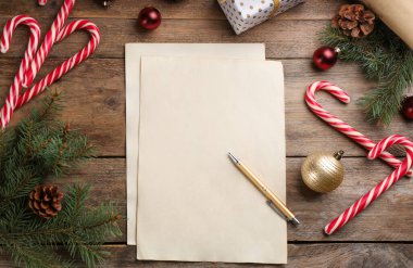 Tahta masa üzerinde kağıt ve Noel dekoru olan düz bir kompozisyon. Noel Baba 'ya mektup yazıyorum.