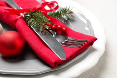 Güzel bulaşık takımları ve beyaz arka planda Noel dekoruyla şenlik masası.