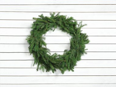 Beyaz ahşap arka planda köknar dallarından yapılmış Noel çelengi