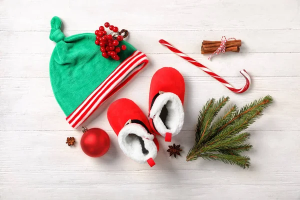 漂亮的婴儿靴 小精灵帽和白色木制背景的圣诞装饰品 — 图库照片
