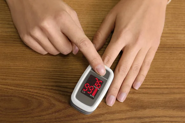 Vrouw Met Behulp Van Pulsoximeter Voor Zuurstofniveau Testen Aan Houten — Stockfoto