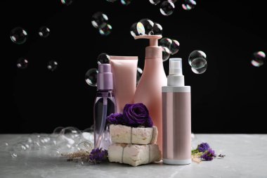 Set of hair cosmetic products, flowers and soap bubbles on black background clipart
