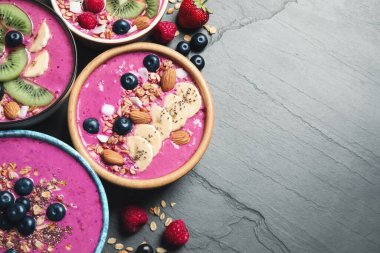 Acai smoothie kaseleri, tahıl gevreği ve siyah masada meyveler, düz uzanma. Metin için boşluk