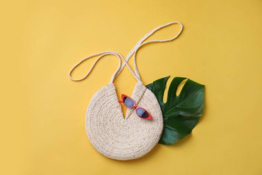 Sarı arka planda saman torbası ve güneş gözlüğü var. Yaz aksesuarları