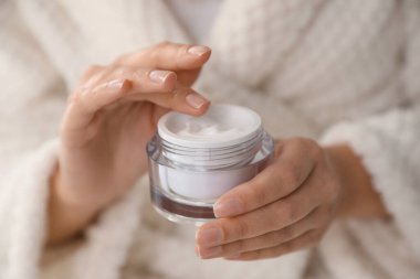 Elinde bir kavanoz nemlendirici krem olan kadın, yakın plan.
