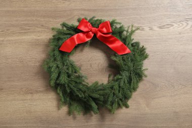 Noel çelengi köknar dallarından yapılmıştır. Ahşap arka planda kırmızı fiyonk vardır.